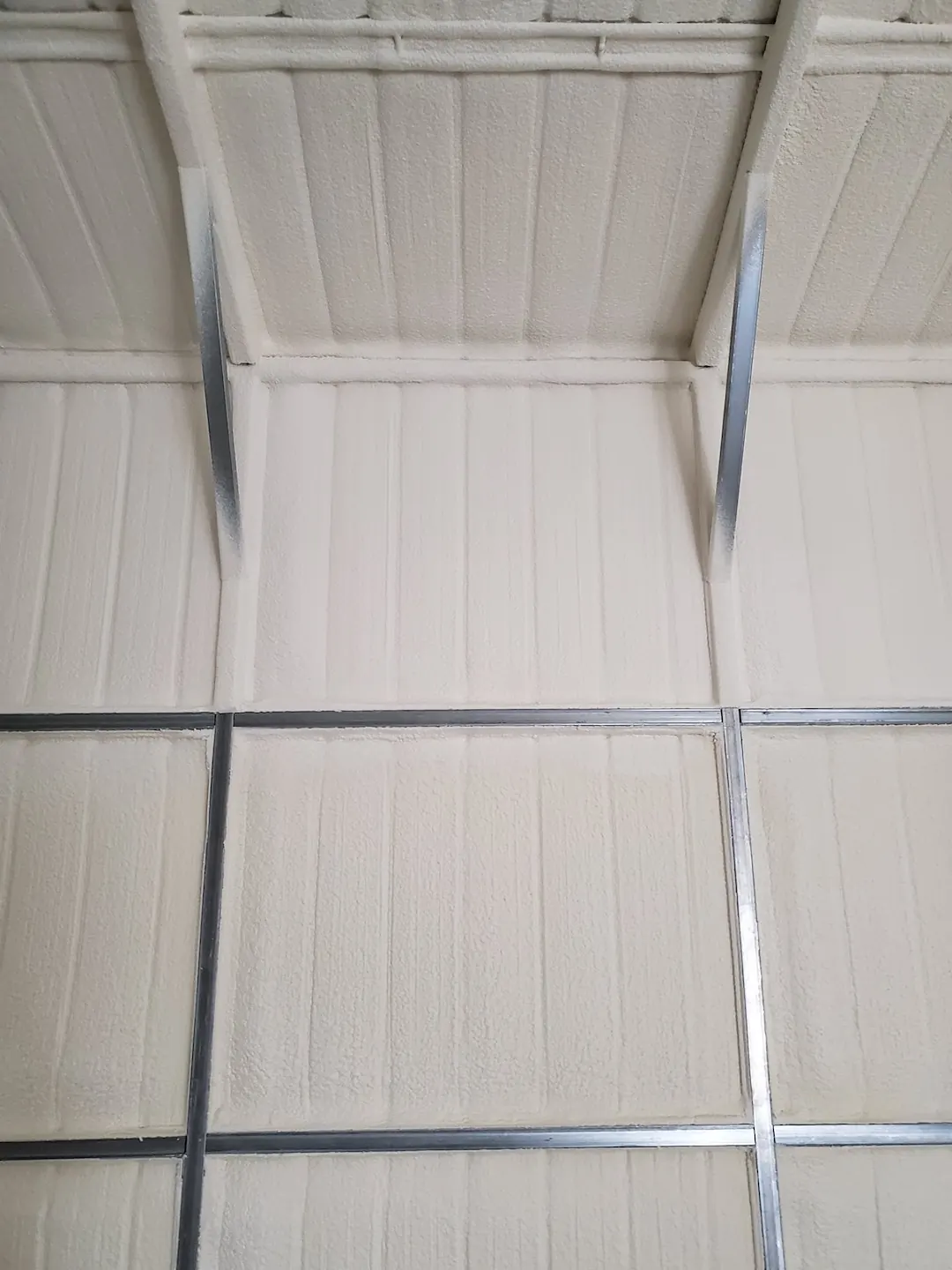 Insulated interior of a commercial metal building, showing the finished foam surface across the wall and roof panels