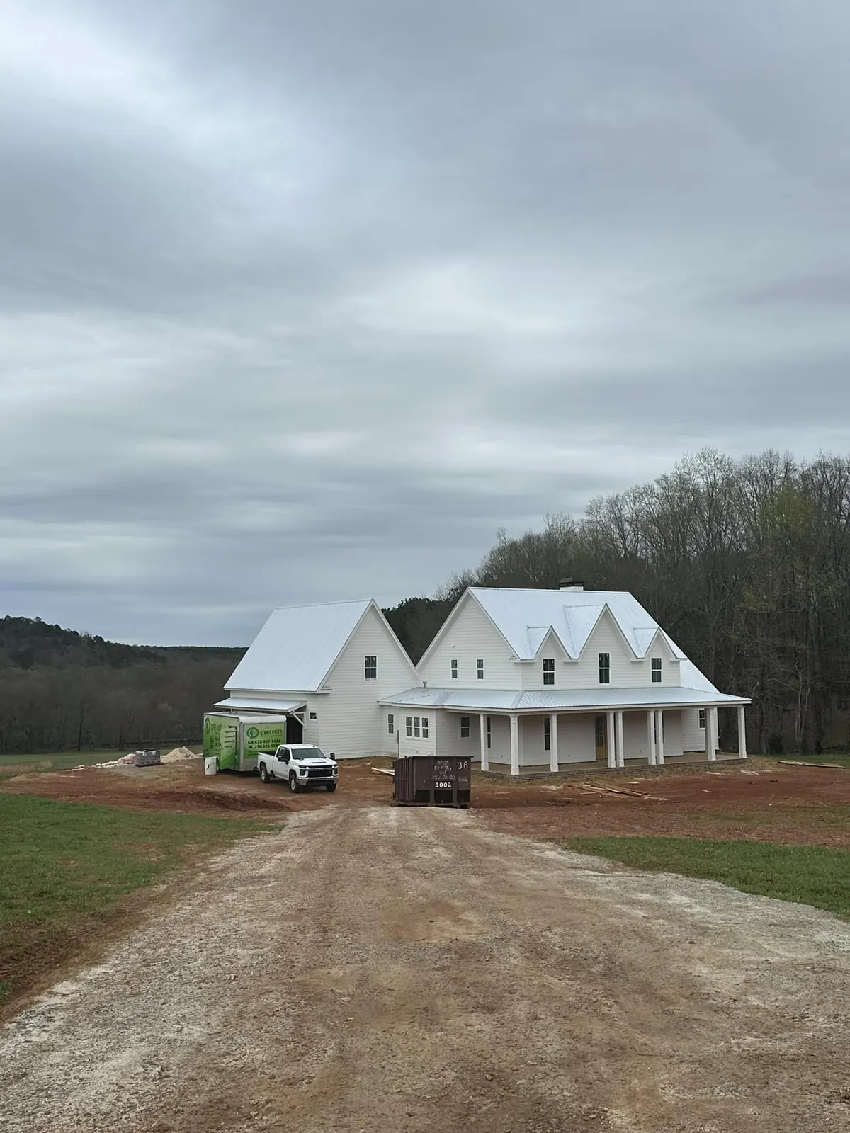 New farmhouse under construction on a rural site, with the Green Earth crew vehicle parked alongside